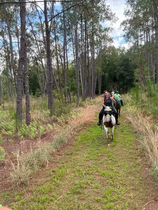A group of Tree House Farm riders traveling a wooded Florida trail